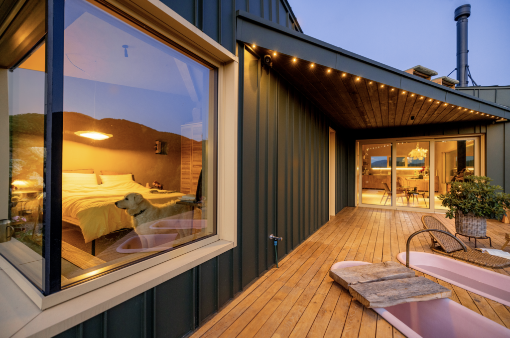 Cabin rental with a lit wooden deck at dusk