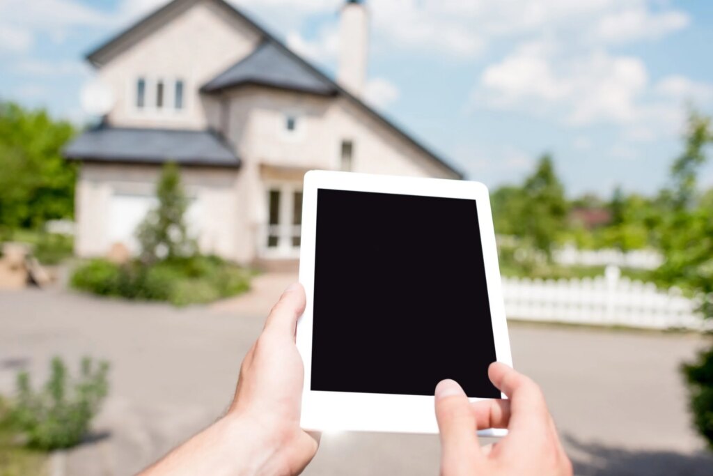 Host holding a tablet in front of a rental home